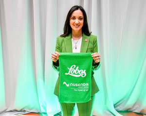 Michelle Dearholt holding a rally towel that says Lobos that is Nusenda green with their logo